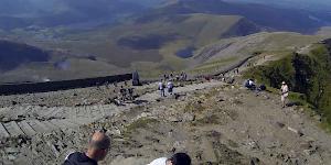 Picture of a comparatively quiet day on Snowdon summit mid summer. View from the summit trig point along the railway line into the valley.