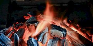 Image showing a warming log fire against a brick wall background.